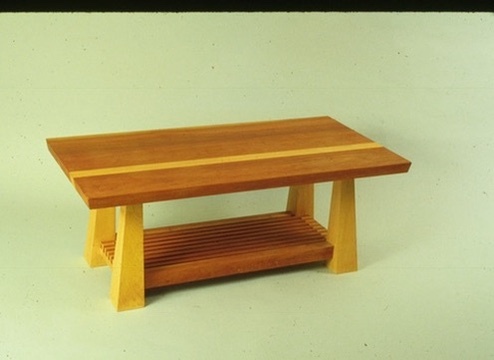 A coffee table with a striped hardwood top, a slatted lower shelf, and splayed legs
