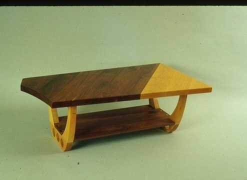 A coffee table whose dark and light woods meet on a diagonal across the top, on curved runners